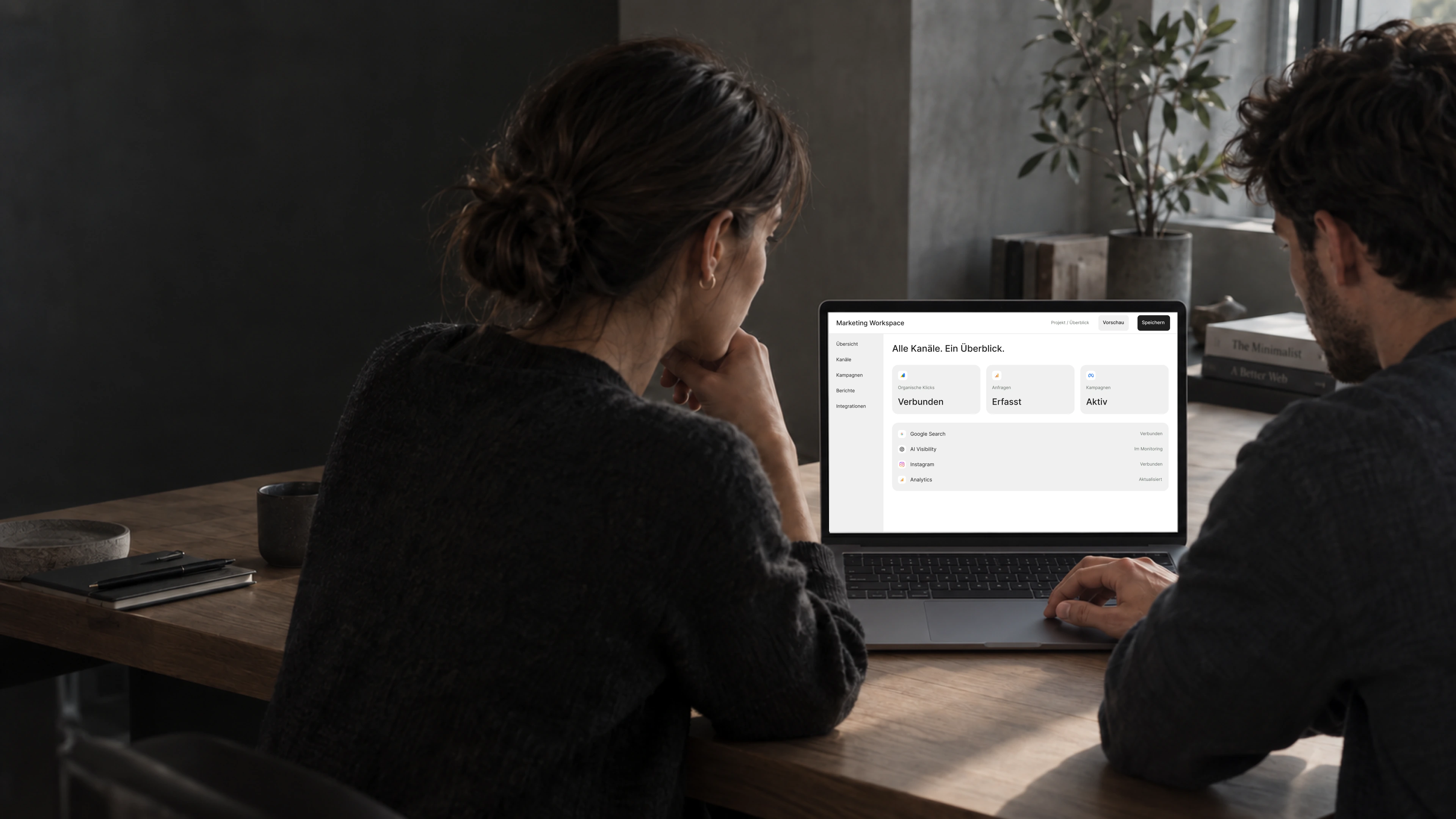 Zwei Personen am Laptop mit einer kanalübergreifenden Marketingübersicht.